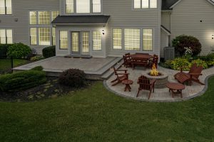 Rear of home with a deck and steps, a custom patio with pavers, stamped concrete, and a fire pit